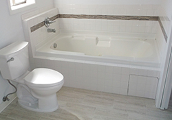 Bathtub with white tile and chrome hardware and a white toilet