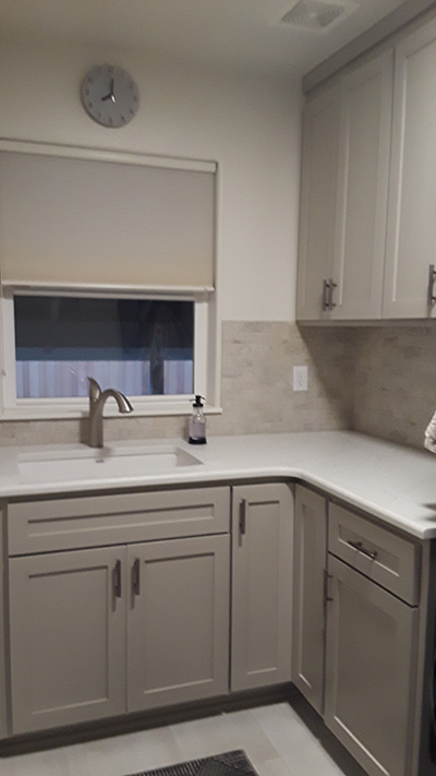 Angled view of sink, window, and more cabinets